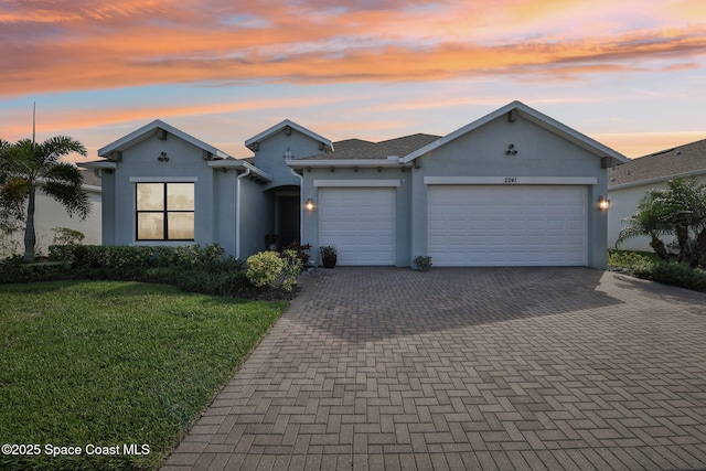 view of front of property with a garage, a front lawn, decorative driveway, and stucco siding