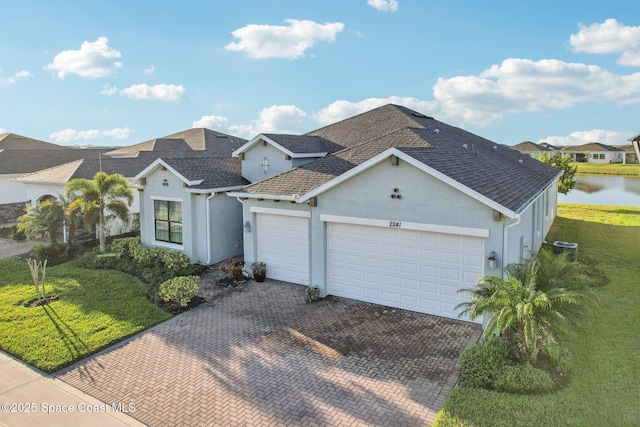 view of front of house with a garage, a shingled roof, decorative driveway, and a front yard