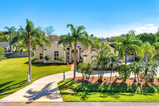 view of front facade with concrete driveway, fence, a front lawn, and stucco siding