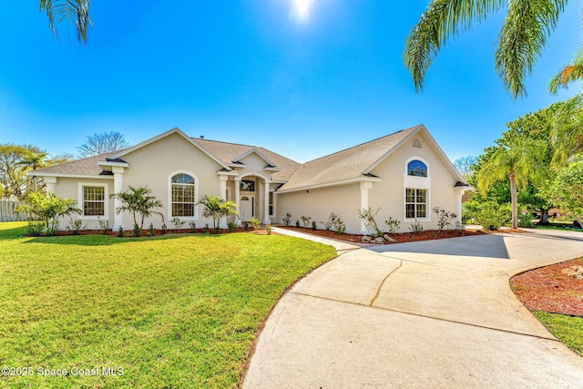 view of front of house featuring driveway, roof with shingles, a front yard, and stucco siding