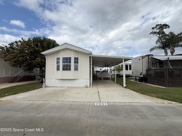 manufactured / mobile home with a front lawn and a carport