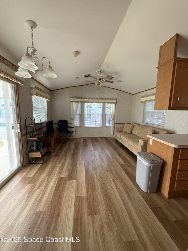 unfurnished living room featuring ceiling fan, vaulted ceiling, plenty of natural light, and light hardwood / wood-style flooring