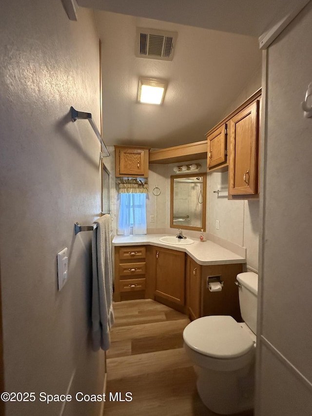 bathroom with toilet, vanity, and hardwood / wood-style floors