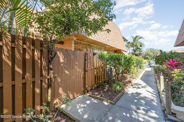 view of property exterior with fence and mansard roof