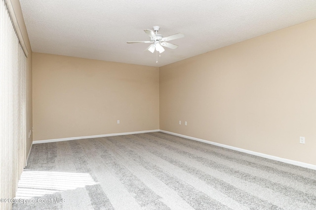 carpeted empty room with a textured ceiling, ceiling fan, and baseboards