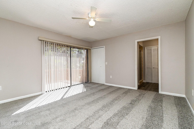 carpeted empty room featuring baseboards, ceiling fan, and a textured ceiling