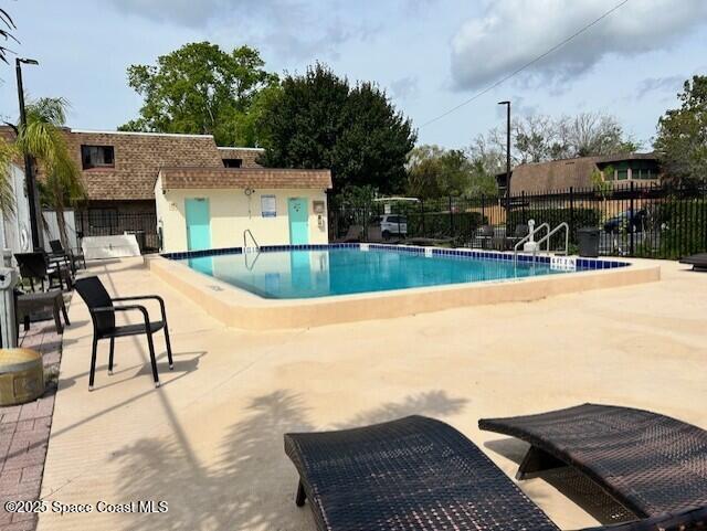 community pool with a patio area and fence