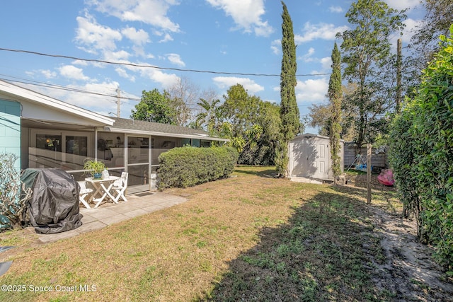 view of yard with a shed, a patio, and a sunroom