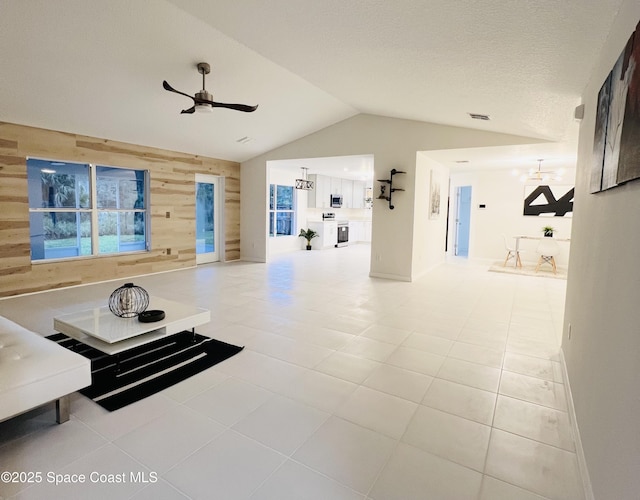 unfurnished living room with tile patterned floors, lofted ceiling, wooden walls, and ceiling fan