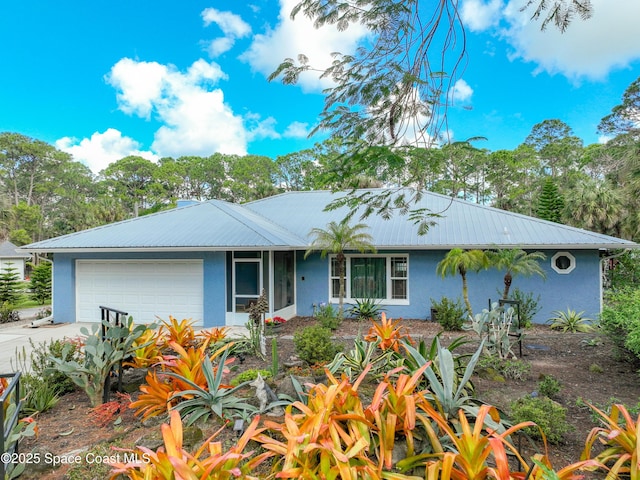 ranch-style home with a garage, metal roof, concrete driveway, and stucco siding