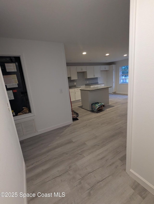 kitchen with a center island, light wood-type flooring, and tasteful backsplash