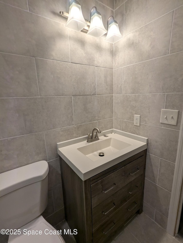 bathroom with tile walls, vanity, and toilet