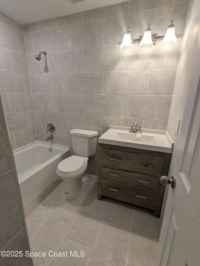 full bathroom featuring tile patterned floors, toilet, tile walls, tiled shower / bath, and vanity