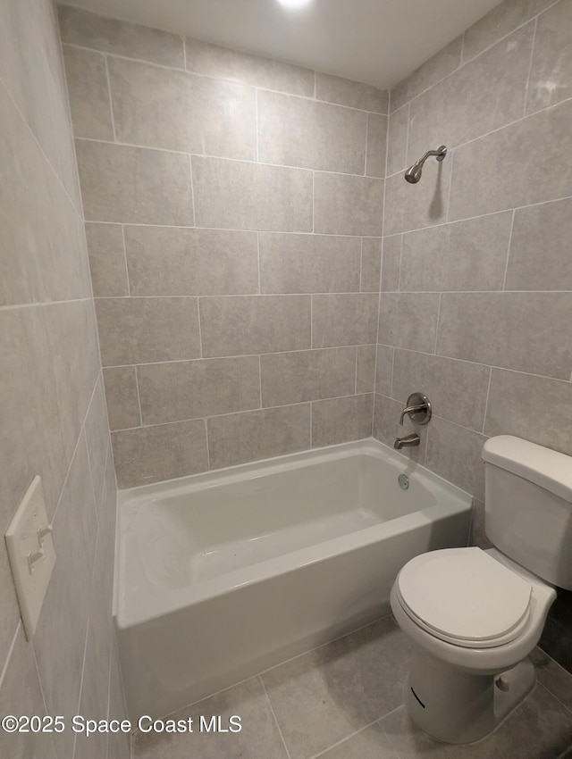 bathroom with tile patterned flooring, toilet, and tiled shower / bath