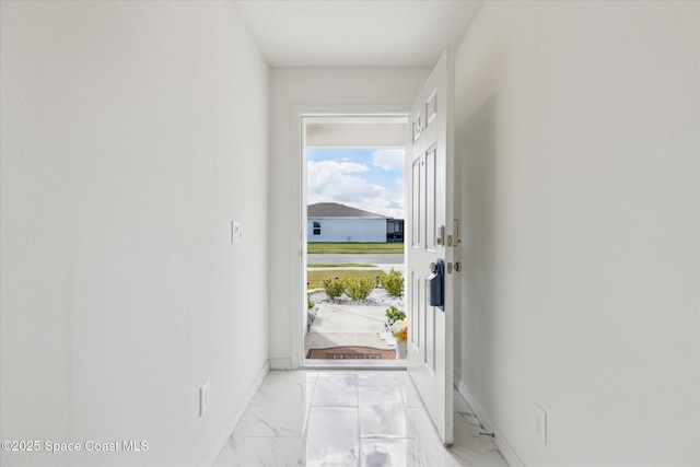 doorway to outside with marble finish floor and baseboards