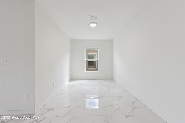 empty room with marble finish floor, visible vents, and baseboards