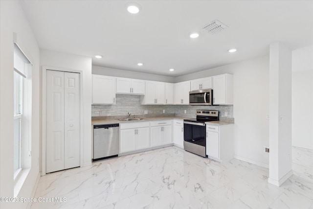 kitchen featuring marble finish floor, appliances with stainless steel finishes, white cabinets, and light countertops