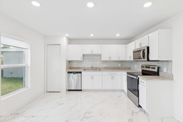 kitchen featuring marble finish floor, appliances with stainless steel finishes, a wealth of natural light, and a sink