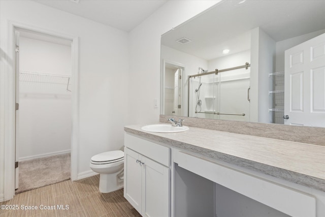 full bath featuring toilet, vanity, baseboards, a spacious closet, and a shower stall