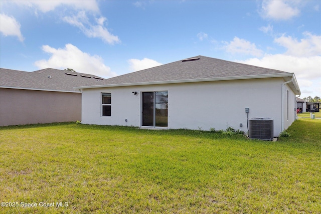 rear view of property with roof with shingles, a lawn, stucco siding, and central air condition unit