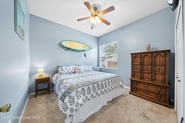 bedroom with light carpet, ceiling fan, and a textured ceiling