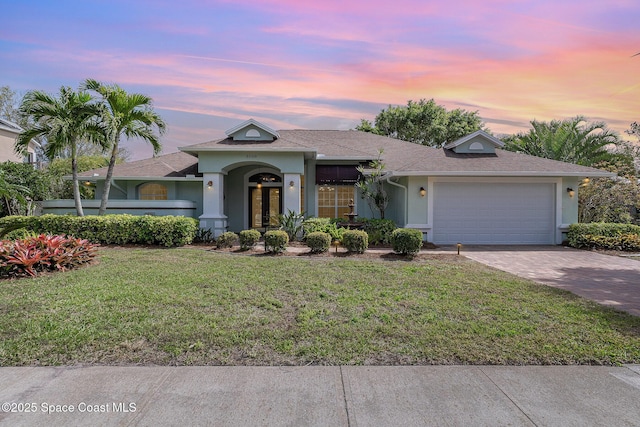 view of front of property featuring an attached garage, decorative driveway, a lawn, and stucco siding