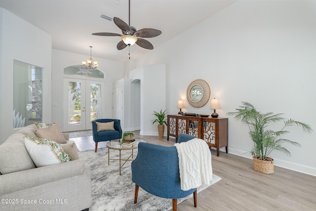 living room with light wood finished floors, baseboards, high vaulted ceiling, and french doors