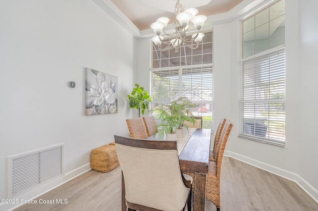 dining area with an inviting chandelier, baseboards, visible vents, and wood finished floors