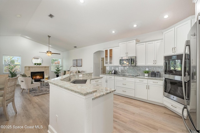 kitchen featuring stainless steel appliances, a premium fireplace, a sink, visible vents, and white cabinets