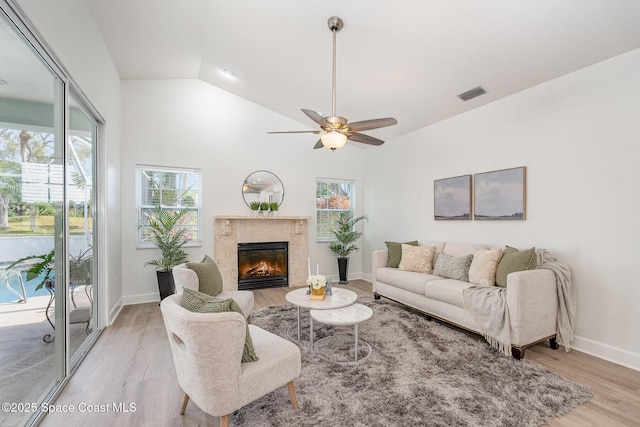 living area with a healthy amount of sunlight, light wood finished floors, visible vents, and a high end fireplace