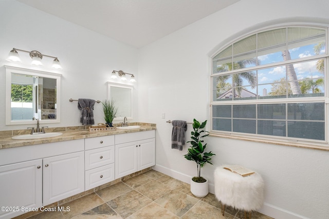 full bathroom with double vanity, a sink, and baseboards