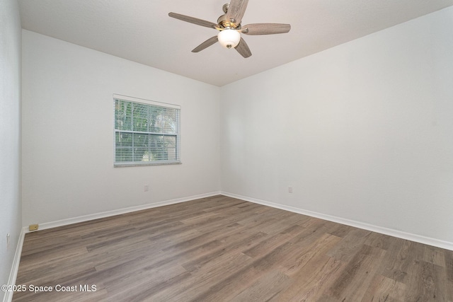 spare room featuring ceiling fan, baseboards, and wood finished floors