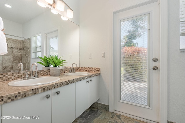 full bath with double vanity, marble finish floor, and a sink