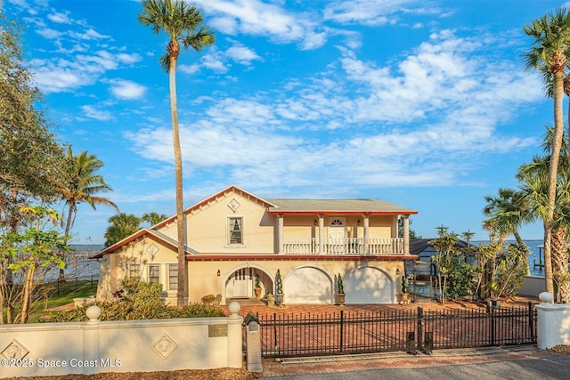 mediterranean / spanish home featuring a balcony, a fenced front yard, a gate, and stucco siding