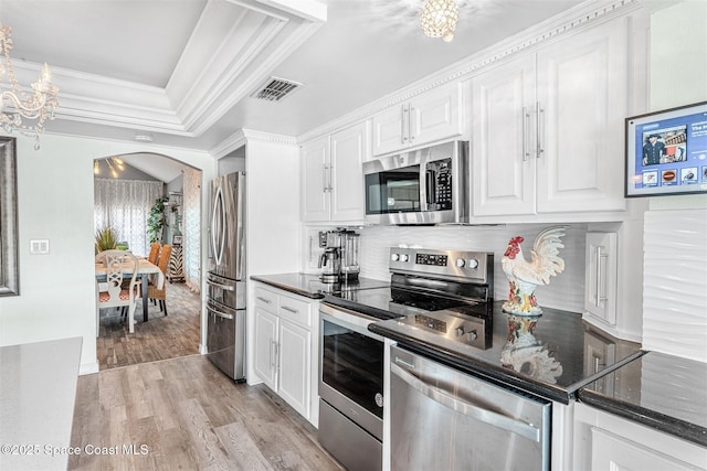 kitchen featuring visible vents, arched walkways, stainless steel appliances, light wood-style floors, and white cabinetry