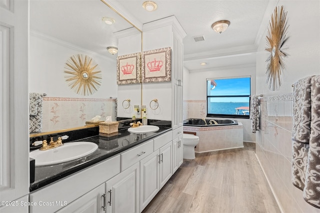 full bathroom featuring a garden tub, wood finished floors, a sink, double vanity, and crown molding