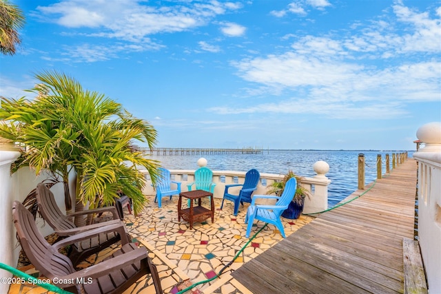 view of dock with a patio and a water view