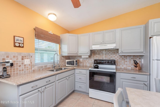 kitchen with electric stove, white microwave, freestanding refrigerator, under cabinet range hood, and a sink