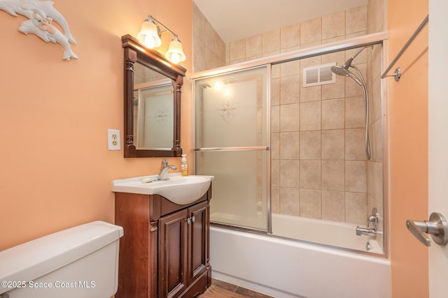 bathroom featuring toilet, shower / bath combination with glass door, vanity, and visible vents