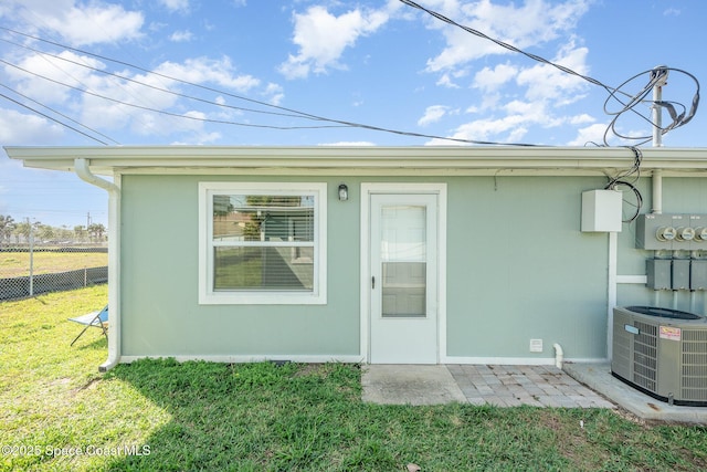 doorway to property featuring a yard, fence, and central AC unit