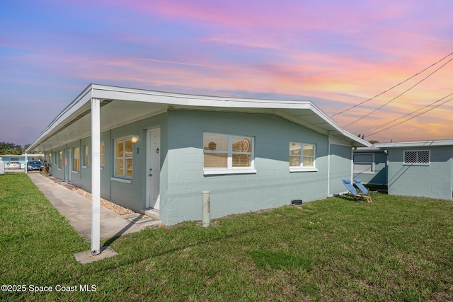 view of property exterior with concrete block siding and a yard