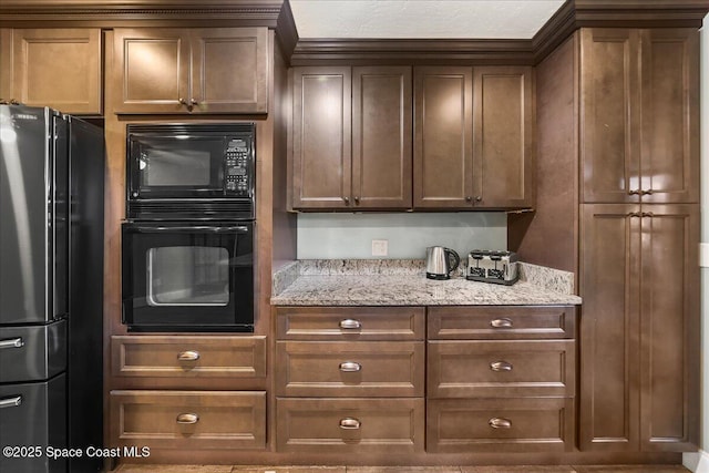 kitchen featuring black appliances and light stone counters