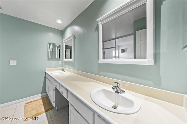 full bath featuring double vanity, a sink, baseboards, and tile patterned floors