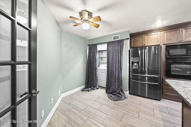 kitchen with ceiling fan, light stone counters, visible vents, black appliances, and washer / clothes dryer