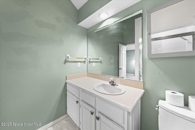 bathroom featuring toilet, baseboards, and vanity