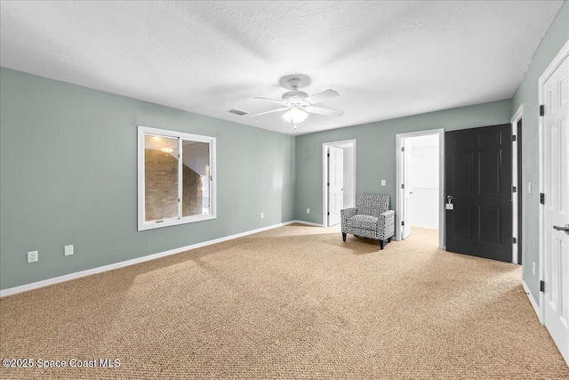 unfurnished room with a textured ceiling, carpet flooring, a ceiling fan, visible vents, and baseboards