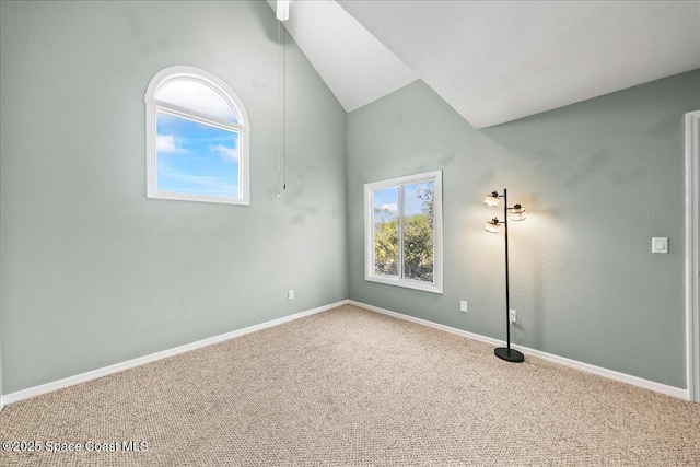 carpeted spare room featuring lofted ceiling and baseboards