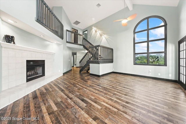 unfurnished living room with high vaulted ceiling, wood finished floors, beam ceiling, and baseboards