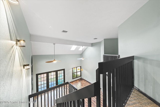 staircase with a skylight, visible vents, wood finished floors, high vaulted ceiling, and beamed ceiling