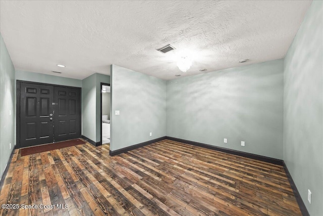 unfurnished room featuring baseboards, visible vents, and dark wood finished floors